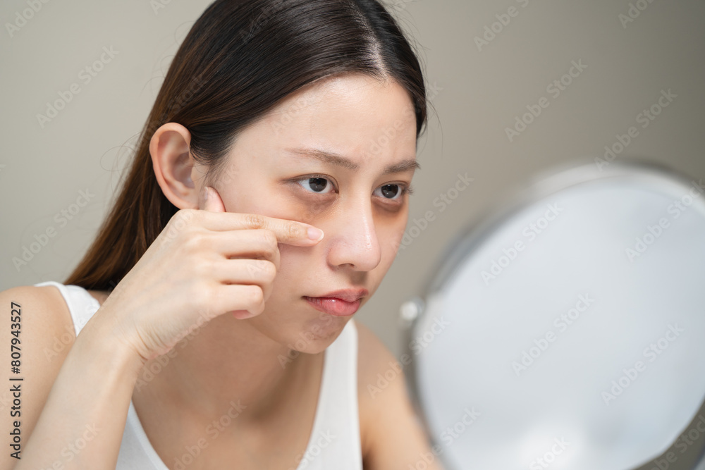 Bored, insomnia asian young woman, girl looking at mirror hand touching under eyes with problem of black circles or panda puffy, swollen and wrinkle on face. Sleepless, sleepy healthcare person. Bored, insomnia asian young woman, girl looking at mirror hand touching under eyes with problem of black circles or panda puffy, swollen and wrinkle on face. Sleepless, sleepy healthcare person.