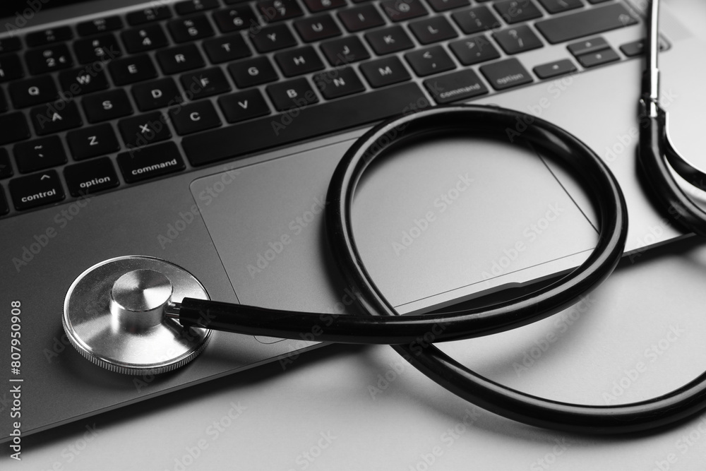 Laptop and stethoscope on light grey background, closeup Laptop and stethoscope on light grey background, closeup