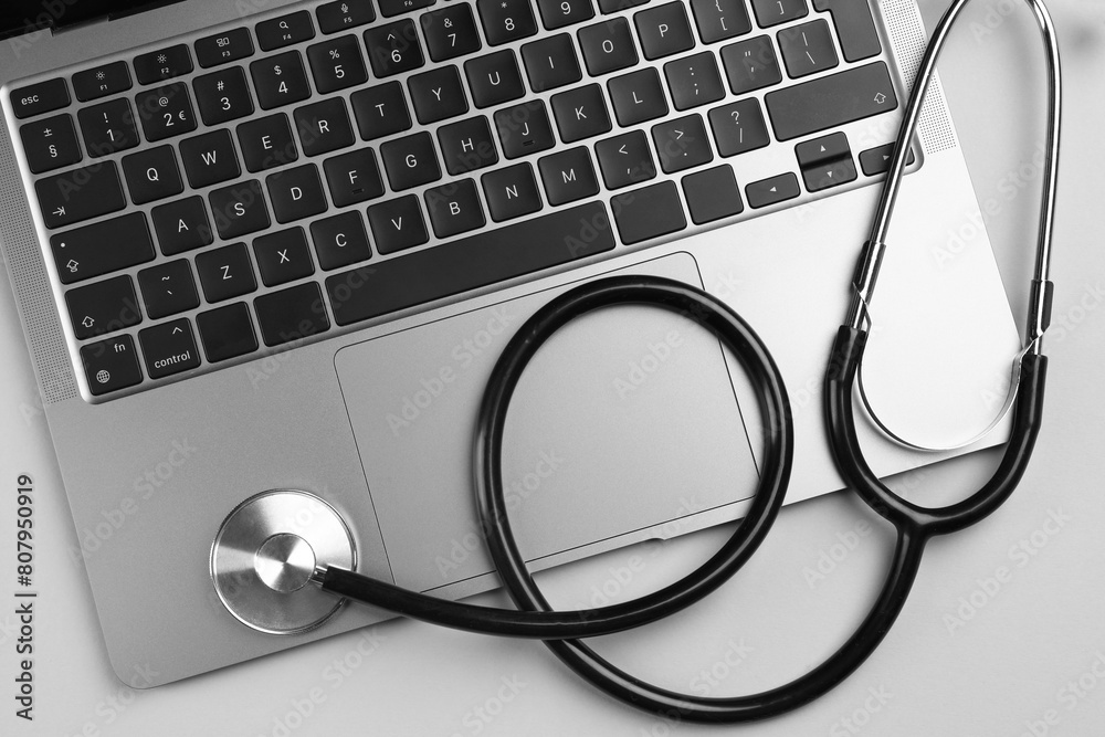 Laptop and stethoscope on light grey background, flat lay Laptop and stethoscope on light grey background, flat lay