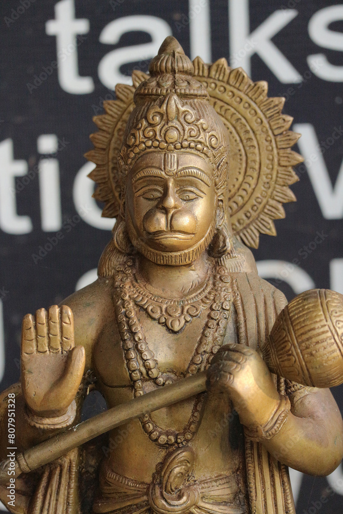 Obraz premium Bronze figurine of Hanuman with a mace and a blessing gesture on a dark background.