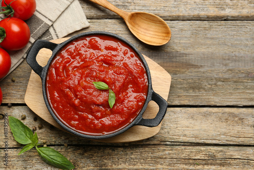 Tableau sur toile Homemade tomato sauce in bowl, spoon and fresh ingredients on wooden table, flat lay