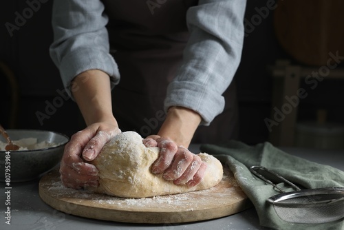 Woman kneading dough at grey table, closeup