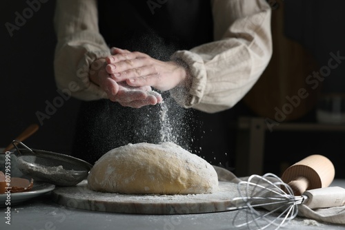 Making dough. Woman adding flour at grey table, closeup