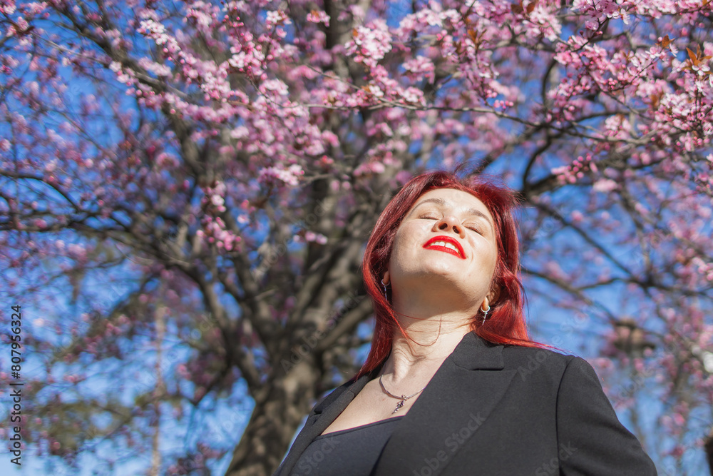 Woman with cherry flowers surrounded by blossoming trees copy space. Beauty and seasonal change and spring bloom season concept. Woman with cherry flowers surrounded by blossoming trees copy space. Beauty and seasonal change and spring bloom season concept.