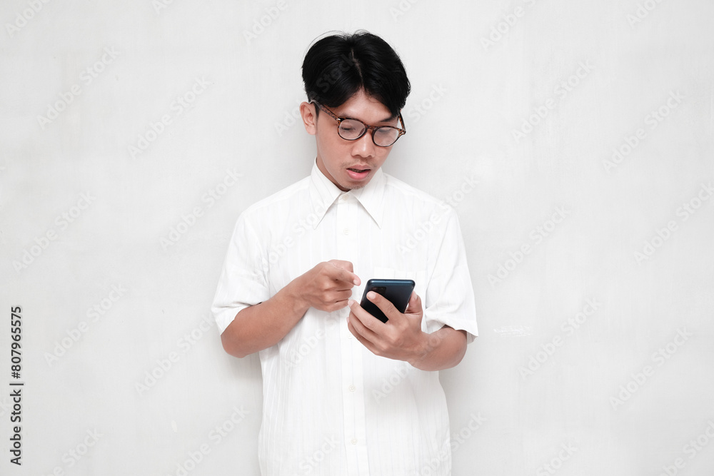 Asian man in white shirt shocked pointing at cell phone Asian man in white shirt shocked pointing at cell phone