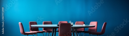 A large round table with multiple chairs around it, symbolizing inclusivity and discussion, set against a conference room blue background.