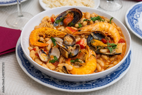 A traditional Alentejo restaurant serves a vibrant seafood feijoada. This dish features prawns, shellfish, and beans in a rustic clay pot, offering a hearty and authentic Portuguese experience.