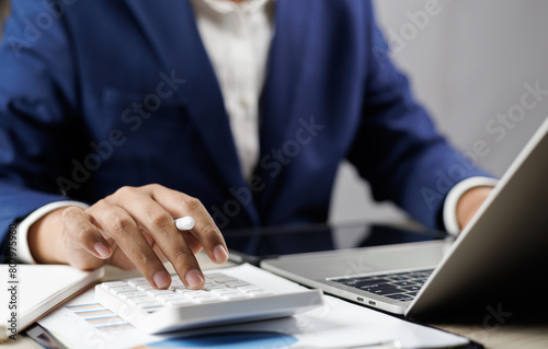 Businessman calculating taxes and finances on laptop at corporate desk, Financial success, Accountant working with calculator and paperwork ,Economy concept. Man managing budget and market statistics. © GamePixel