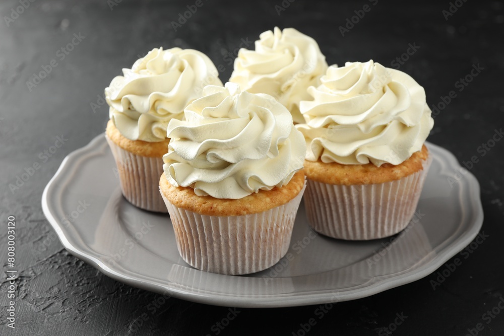 Tasty cupcakes with vanilla cream on black table, closeup Tasty cupcakes with vanilla cream on black table, closeup