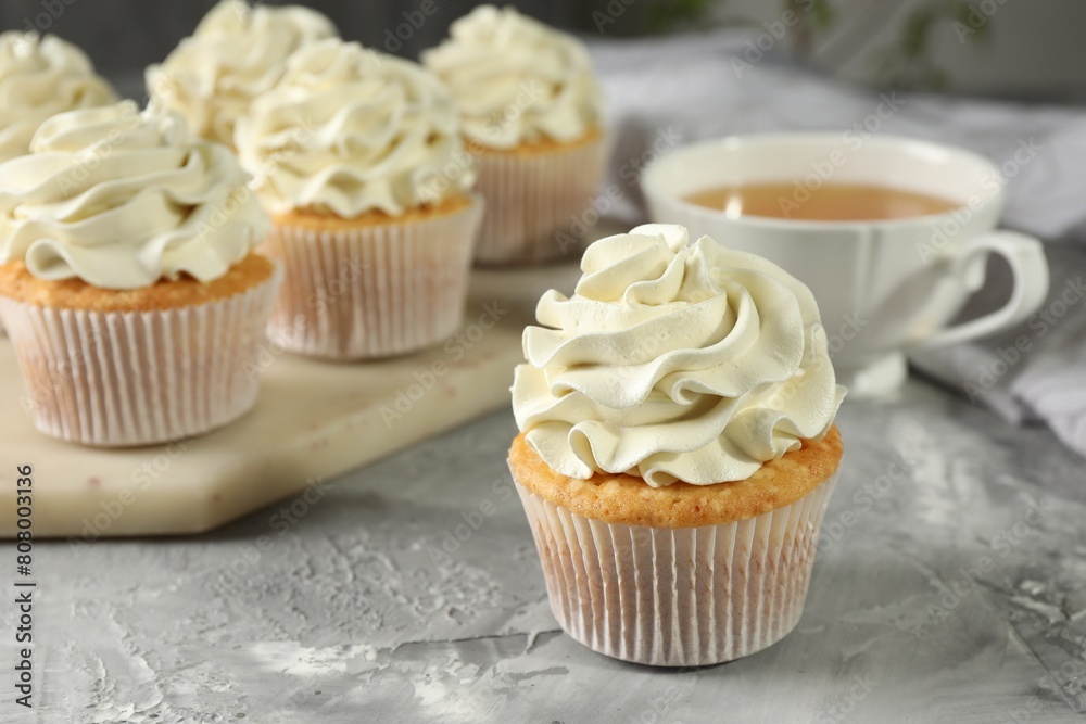 Tasty cupcakes with vanilla cream on grey table, closeup Tasty cupcakes with vanilla cream on grey table, closeup