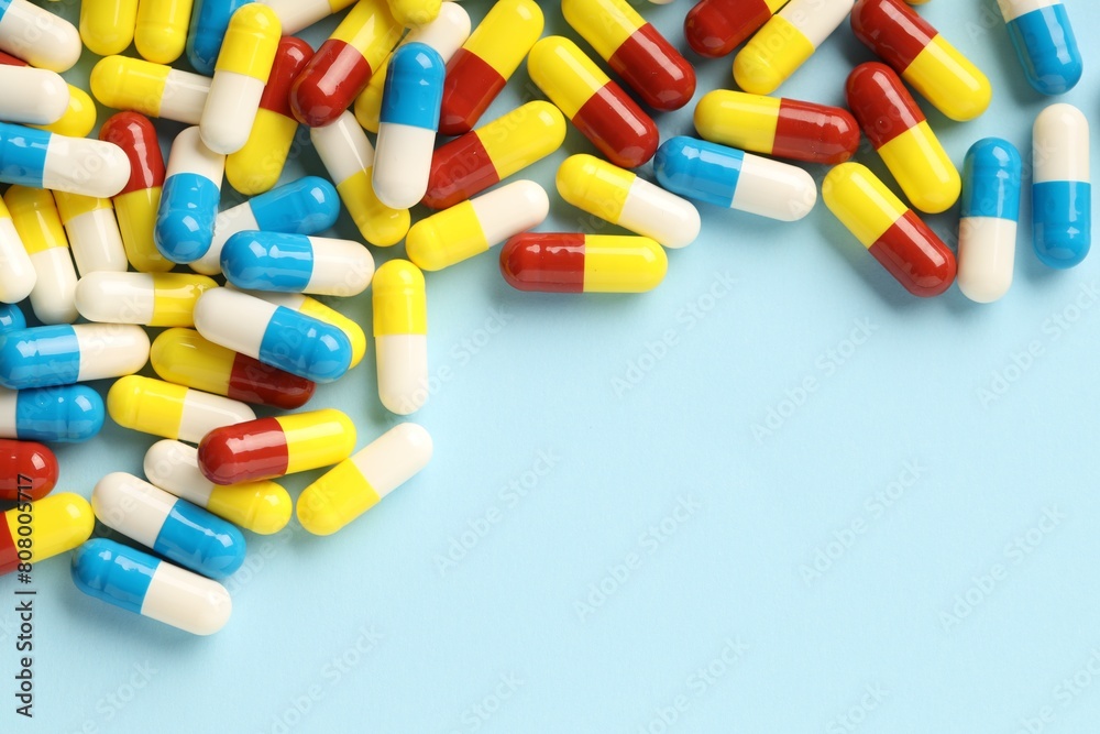 Many antibiotic pills on light blue background, top view. Space for text Many antibiotic pills on light blue background, top view. Space for text
