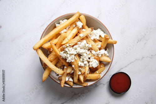 Bowl of hot chips with sprinkled feta cheese and side of tomato sauce photo