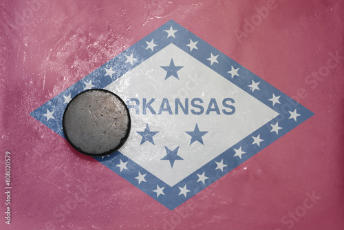 old hockey puck is on the ice with national flag of arkansas state. photo