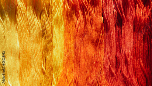 Gradient transition from yellow to red on floss threads.