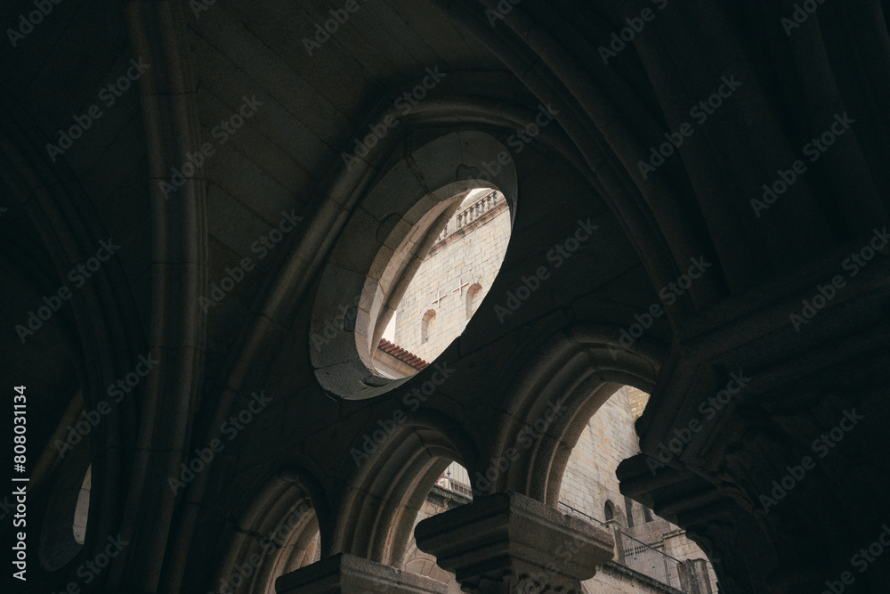 The inner courtyard of Porto Cathedral is bathed in a serene, diffuse light, casting soft shadows around the ornate architecture of the arches and columns