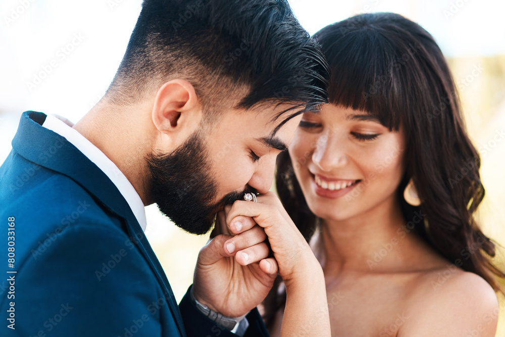 Fototapeta premium Couple, love and wedding ring in outdoors, kiss and symbol for promise of loyalty or commitment. People, fingers and nature or celebrate for partnership, support and trust in marriage or relationship