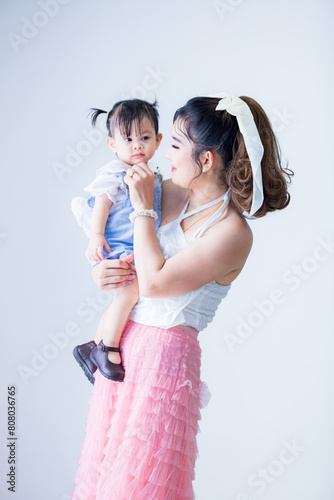 Asian mother and daughter isolated on white background,cheerful asian toddler daughter hugging happy mother isolated on gray 