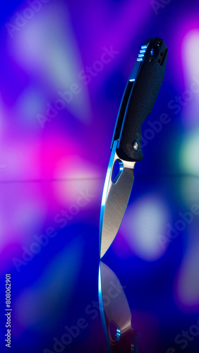 Pocket knife. Cyberpunk style. The background is colored, blurry.