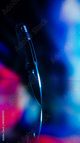 Pocket knife. Cyberpunk style. The background is colored, blurry.