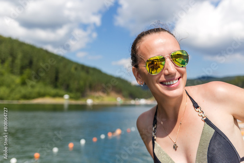 Young smiling woman near the mountain lake in the summer