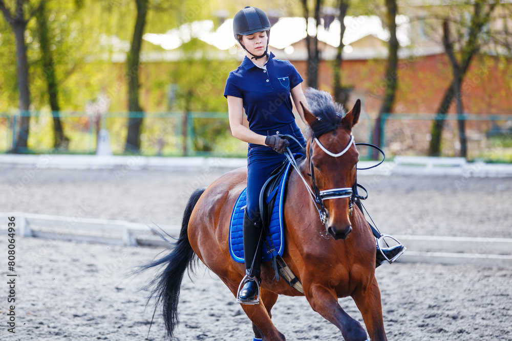 Young girl riding bay horse on equestrian dressage training Young girl riding bay horse on equestrian dressage training