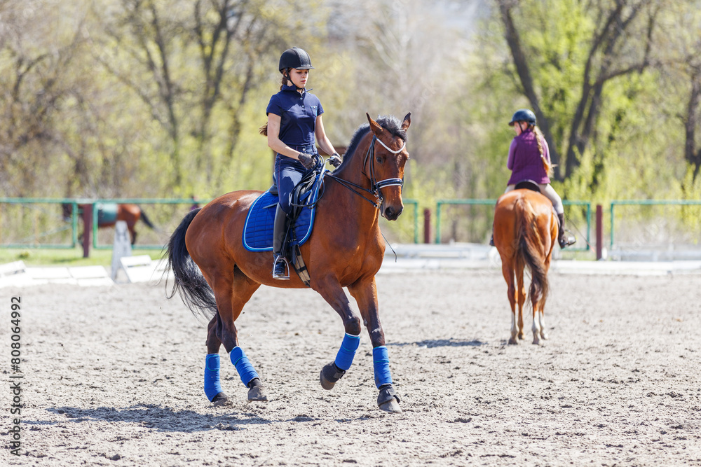 Young girl riding bay horse on equestrian dressage training Young girl riding bay horse on equestrian dressage training