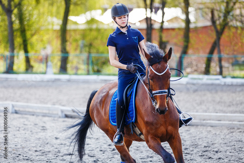 Young girl riding bay horse on equestrian dressage training © skumer