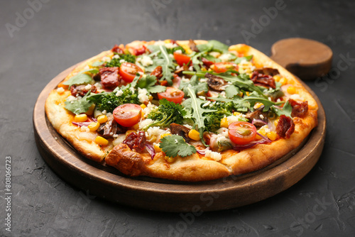 Delicious vegetarian pizza with cheese, mushrooms, vegetables and greens on black table