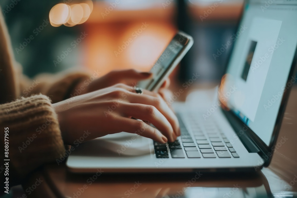 Close-up of a person using a laptop and a smartphone. Close-up of a person using a laptop and a smartphone.