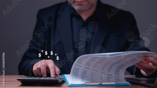 Banking manager is sitting at a desk with a calculator and a stack of papers. He is looking at the papers and seems to be calculating something, loan, money, finance, interest, Stock, funds