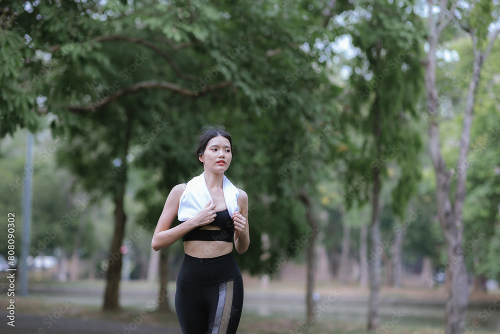 Young Asian woman running hard on the street at the park after daily exercise. Jogging to keep fit on a warm summer morning. Young Asian woman running hard on the street at the park after daily exercise. Jogging to keep fit on a warm summer morning.