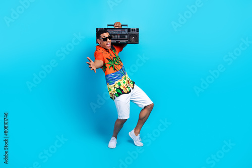 Full length photo of funky carefree guy dressed print shirt having fun listening boom box isolated blue color background