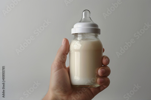 Isolated baby bottle feeding full of milk in woman hand on white background