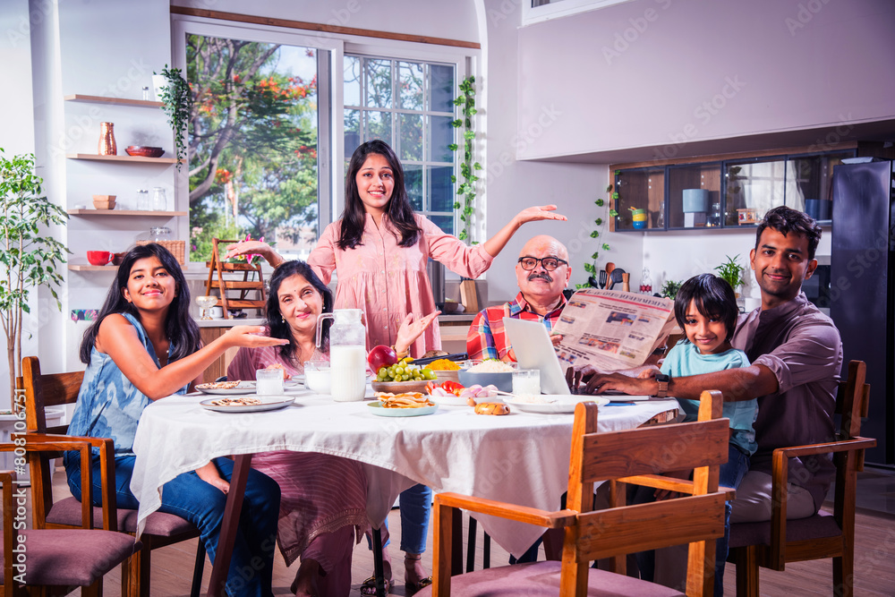 Obraz premium Indian family having lunch at home on dining table with grandparents, parents and kids