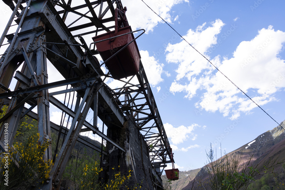 Abandoned industrial coal mining cart on cableway with rusty metal tower with cable on a bright sunny spring day with flower meadow Abandoned industrial coal mining cart on cableway with rusty metal tower with cable on a bright sunny spring day with flower meadow