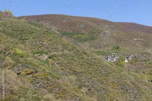 Stone cortin round abandoned beehive protection structure from bears in mountain landscape on a bright sunny spring day with flowers photo