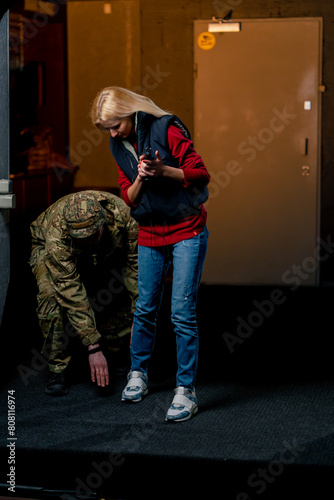 in a professional shooting range military man tells and shows a girl what the correct stance with a pistol is