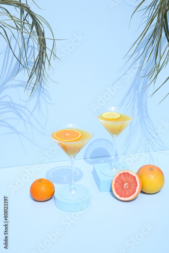 Summer drink with fruits on a blue background with palms and shadows. Sweet aesthetic beverage concept.