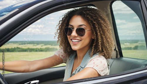 Happy brunette girl wearing sunglasses driving a modern car with curly hair and a carefree smile, enjoying the freedom of the open road  © Martina