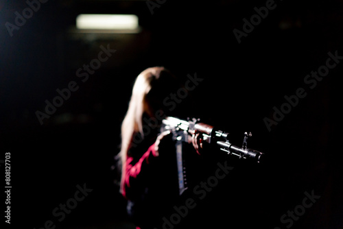 tactical strategy military girl stands with rifle aiming in the dark contrast light back light silhouette