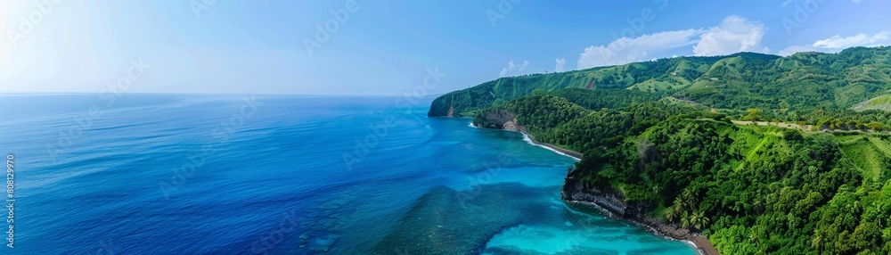 Aerial view of a stunning turquoise coastline lush green hills under a bright blue sky. High-angle shot