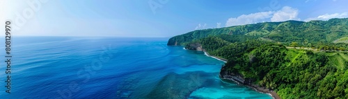Aerial view of a stunning turquoise coastline lush green hills under a bright blue sky. High-angle shot