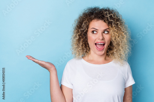 Photo of amazed lady hold hand show blank space look away open mouth wear casual shirt isolated blue color background photo