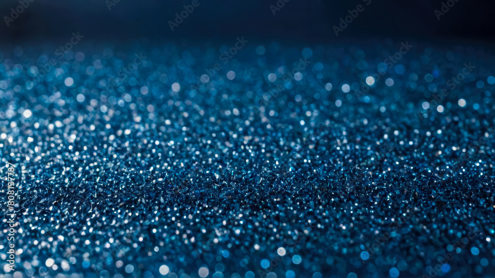 Festive background made of scattering of decorative blue particles. Shiny glass or stone small crystal elements with bokeh. Perfect abstract backdrop.