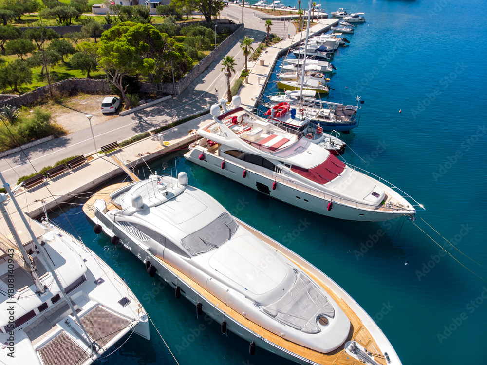 Scenic aerial view many yachts boats moored at Croatian bay harbor shore blue turquoise clear water at bright summer sunny day. Top above Mediterranean sea marina. Boat vessel charter service