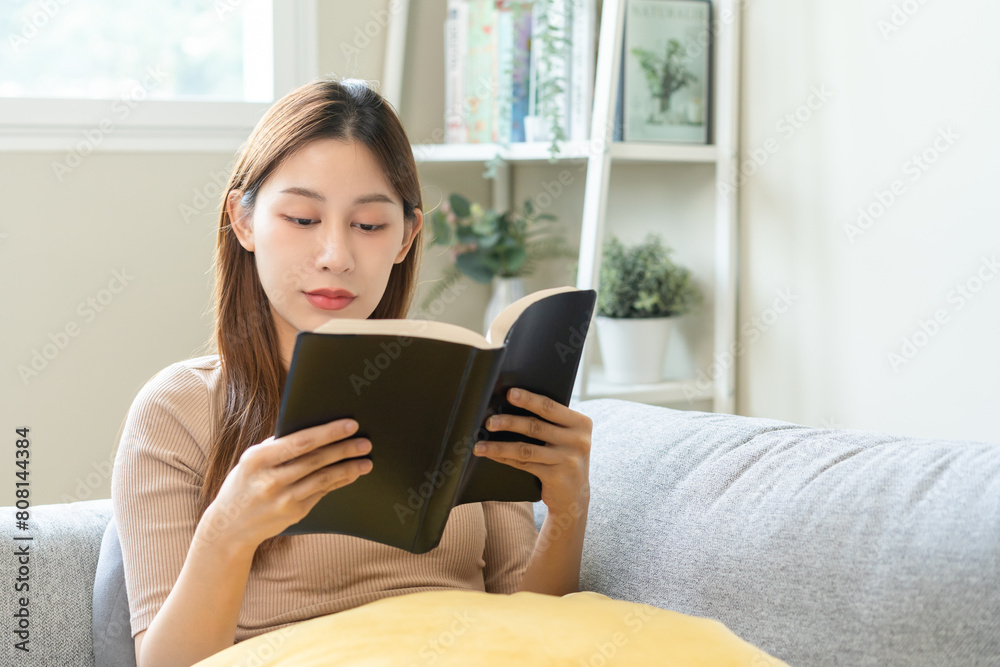 Having relaxing weekend, comfort asian young woman with cup of beverage, drinking coffee or tea of mug. Girl sitting on sofa open reading book enjoy of rest after get up in morning lifestyle at home. Having relaxing weekend, comfort asian young woman with cup of beverage, drinking coffee or tea of mug. Girl sitting on sofa open reading book enjoy of rest after get up in morning lifestyle at home.
