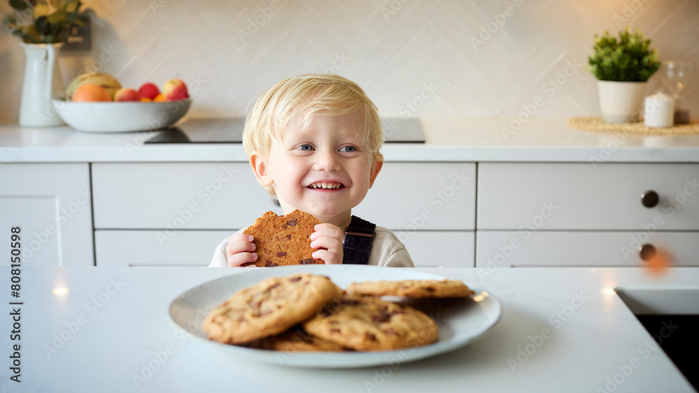 Mischievous Young Boy Eating Giant Cookie From Plate In Kitchen At Home