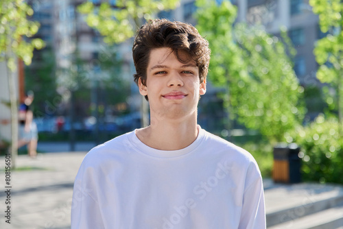 Fotografie Headshot portrait of handsome guy 19, 20 years old, looking at camera outdoors