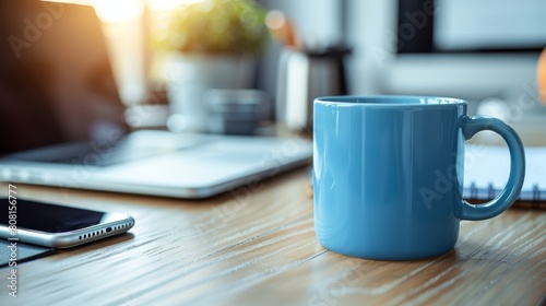   A blue coffee mug rests atop a weathered wooden table Nearby, a cell phone and laptop are positioned on a desk