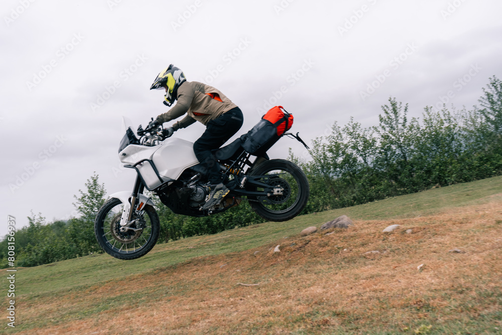 Motorcyclist jumping in moto trip on adventure tourist enduro motorcycle outdoor offroad in mountains Motorcyclist jumping in moto trip on adventure tourist enduro motorcycle outdoor offroad in mountains